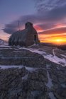 Мальовничий пейзаж маленький старілий кам'яний будинок, розміщений на засніженій вершині гір під барвистим хмарним небом на заході сонця — стокове фото