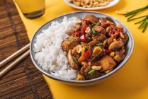 Von oben Komposition Schüssel mit Kung-Pao-Huhn mit weißem Reis Erdnuss und roter Chilischote und grüne Zwiebel und Essstäbchen — Stockfoto