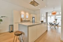 Інтер'єр сучасної кухні з білими меблями і технікою в просторій новій квартирі — стокове фото