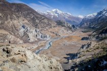 Pintoresco paisaje de río curvo que fluye entre altas montañas empinadas con picos nevados en las tierras altas de Nepal - foto de stock