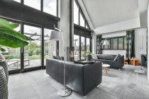 Інтер'єр стильної просторої сіро-кольорової вітальні, обставленої зручними диванами біля скляних дверей — стокове фото