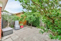 Esterno della moderna casa residenziale con alberi e piante in vaso poste sul marciapiede in cortile in estate — Foto stock