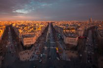 Vue par drone des façades des maisons urbaines et des routes avec transport sous un ciel nuageux brillant au coucher du soleil à Paris France — Photo de stock