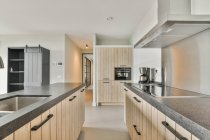 Интерьер кухонной зоны с деревянными шкафами в современной квартире с минималистичным дизайном — стоковое фото