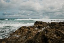 Vista panorâmica do mar ondulado com fluxos de água espumosa contra praia áspera com montanha na Cantábria Espanha — Fotografia de Stock