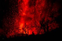 Silhouette umana seduta contro l'esplosione di lava e magma che fuoriesce dal cratere. Cumbre Vieja eruzione vulcanica a La Palma Isole Canarie, Spagna, 2021 — Foto stock