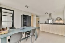 Синій стіл і стільці розміщені біля кухні зі світлими меблями в сучасній квартирі — стокове фото