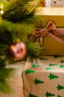 Sammlung von Weihnachtsgeschenken, eingewickelt in Papier und Bänder, die in der Nähe von Tannenzweigen platziert wurden — Stockfoto