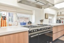 Design creativo di cucina con fornelli elettrici e a gas tra tavoli con utensili da cucina in casa luce — Foto stock