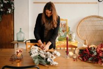 Спокійний жіночий флорист стоїть за столом і влаштовує букет квітів у творчій студії флористики — стокове фото