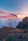 Sonnenaufgang auf mächtigen Berggipfeln inmitten weicher dicker weißer Wolken und im Hintergrund der Ausbruch eines Vulkans. Cumbre Vieja Vulkanausbruch auf La Palma Kanarische Inseln, Spanien 2021 — Stockfoto