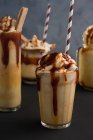 Verschiedene Gläser mit süßem Karamell-Milchshake mit Vanilleeis und Waffelplätzchen auf dem Tisch — Stockfoto