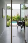 Vaciar amplio pasillo de villa residencial moderna que conduce al patio trasero con piscina y plantas verdes en el día soleado - foto de stock