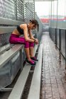 Вид сбоку все тело тонизированной спортсменки в активной одежде, сидящей на скамейке после тренировки на открытом воздухе — стоковое фото