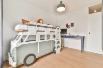 Інтер'єр просторої дитячої спальні зі спальнею у формі автомобіля та білих стін в сучасній квартирі вдень — стокове фото