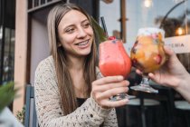 Fröhliche Teenagerinnen interagieren beim Gläschen mit köstlichen Erfrischungsgetränken am Tisch in der städtischen Cafeteria — Stockfoto