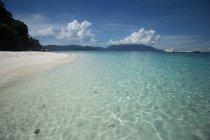 Живописный вид на чистое голубое море, моющий песчаный пляж, окруженный косяками — стоковое фото