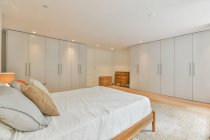 Інтер'єр сучасної спальні зі зручним ліжком і великою шафою в новій квартирі — стокове фото