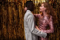 Vue latérale du jeune couple romantique multiracial dans des vêtements élégants embrassant tout en célébrant le réveillon du Nouvel An — Photo de stock