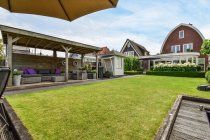 Patio with meadow against residential buildings and couch under roof in Province of Utrecht Netherlands — Stock Photo
