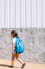 Vista lateral da criança em idade escolar com mochila no pavimento olhando para a frente à luz solar — Fotografia de Stock