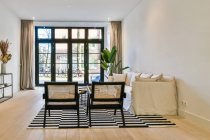 Modernes Interieur mit Sofa und Sesseln auf Teppich mit Streifenornament auf Parkett im Haus — Stockfoto