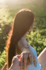 Side view of unrecognizable female adolescent with long hair holding crop best friend by hand in back lit — Stock Photo