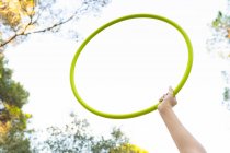 From below of crop unrecognizable female teen in red jeans holding hula hoop while having free time in park — Stock Photo