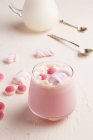 Verre de chocolat blanc chaud sucré avec bonbons à la gelée rose et guimauve servi sur table blanche — Photo de stock