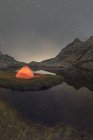 Вид на намет на березі озера на засніжену гору під хмарним небом ввечері — стокове фото