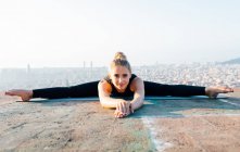 Corpo inteiro de jovem mulher concentrada praticando Upavishta Konasana durante sessão de ioga ao ar livre no telhado ao pôr do sol — Fotografia de Stock