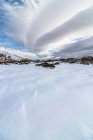 Живописный пейзаж снежной долины со скалами, расположенными в горной местности в зимнее время под облачно-голубым небом при дневном свете — стоковое фото