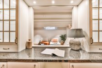 Durch Fenster des zeitgenössischen Interieurs der geräumigen Küche mit Esstisch und verschiedenen Geräten im Ferienhaus — Stockfoto