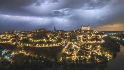 Stadtbild mit betagter berühmter Burg Alcazar von Toledo in Spanien unter bewölktem Himmel in der Nacht während eines Gewitters — Stockfoto
