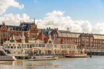 Edifícios de tijolos históricos localizados na margem do rio com barcos ancorados no antigo distrito de Amsterdã — Fotografia de Stock