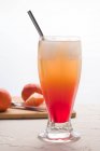 Glass of refreshing Sunrise cocktail with ice cubes and straw served on table with fresh oranges — Stock Photo