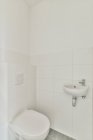 Интерьер современного туалета минималистского стиля с чистым туалетом, установленным на черепичной стене — стоковое фото