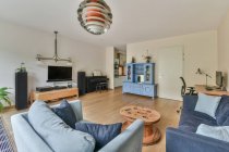 Interior design di ampio soggiorno con divano e televisore appeso sopra lettore musicale in cottage con porte a vetri aperti — Foto stock