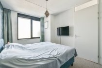 Интерьер современной спальни с большой кроватью с мягкой спинкой возле кровати и стулом под восточной лампой — стоковое фото