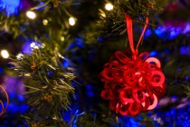 Festive ornament hanging on branch of coniferous tree decorated with garland for Christmas celebration — Stock Photo