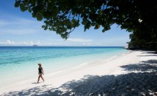 Ethnische Touristin in Badeanzug und Strohhut beim Wandern auf Sand in Malaysia — Stockfoto