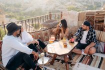 D'en haut de femelle prendre des photos de jeune couple sur appareil photo instantané tout en prenant des cocktails dans le bar avec des amis en terrasse en Cappadoce, Turquie — Photo de stock