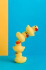 Set di simpatici anatroccoli in gomma e giocattoli mamma anatra collocati su sfondo blu e giallo brillante — Foto stock