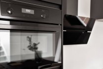 Black modern built in oven with digital time screen near hood in stylish kitchen in modern apartment — Stock Photo
