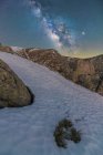 Landschaft aus verschneiten Tälern und Bergen unter nächtlichem Sternenhimmel mit Milchstraße — Stockfoto