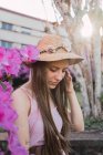 Ніжна жінка-підліток з коричневим волоссям в бісері проти квітучих фіолетових квітів у міському парку — стокове фото