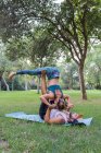 Comprimento total de casal concentrado em activewear fazendo asana enquanto pratica acroyoga juntos no parque verde à luz do dia — Fotografia de Stock