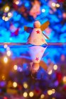 Giocattolo a forma di angelo fatto a mano posto sul tavolo riflettente contro l'albero di Natale festivo con ghirlande incandescenti — Foto stock
