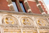 Знизу - декоративний фасад старої будівлі, прикрашений фігурними деталями в Амстердамі. — стокове фото