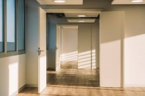 Interior of empty spacious loft hallway with geometrical shadows and sunlight on white walls — Stock Photo